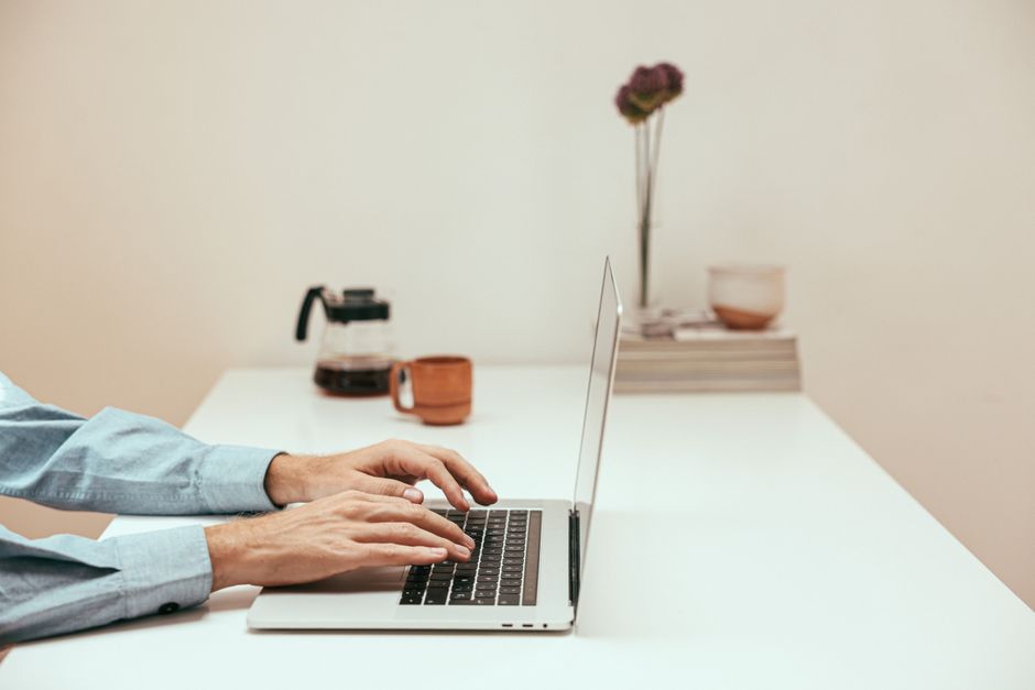 Ruke tipkaju na laptopu u modernom kućnom uredu, simbol suvremenog rada na daljinu