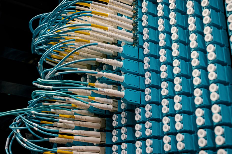 Detaljan pogled na optička patch kabele spojene na plavi patch panel u podatkovnom centru