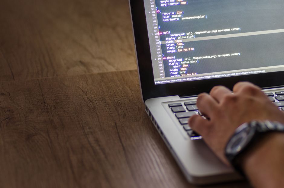 Osoba piše programski kod na laptopu, fokusirana na ekran sa skriptom