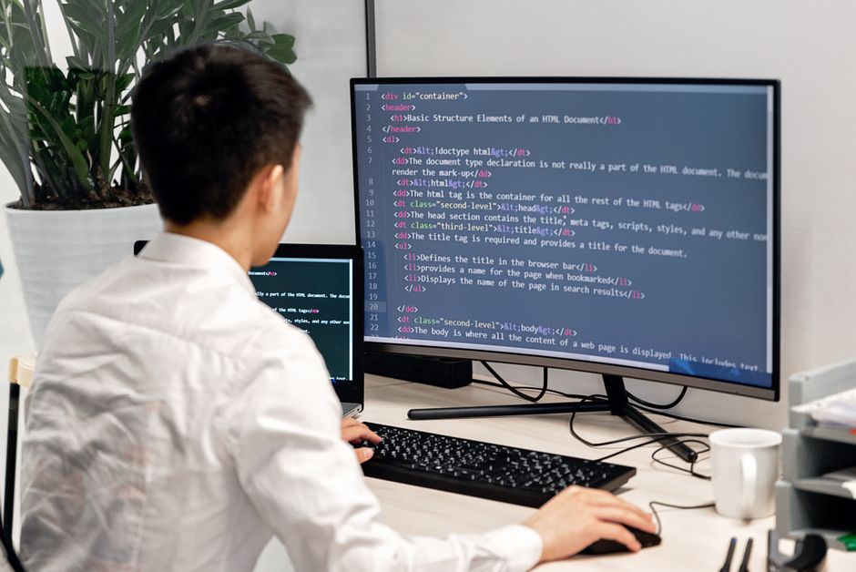 Programer radi na dva monitora u modernom uredskom prostoru